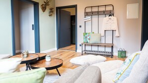 A cozy living room with a sofa, a coffee table, and a hanging coat rack.