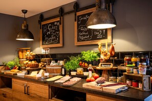 Una encimera de cocina con diversos alimentos, como carnes, verduras y salsas. Hay pizarras con texto, luces colgantes y armarios de madera.