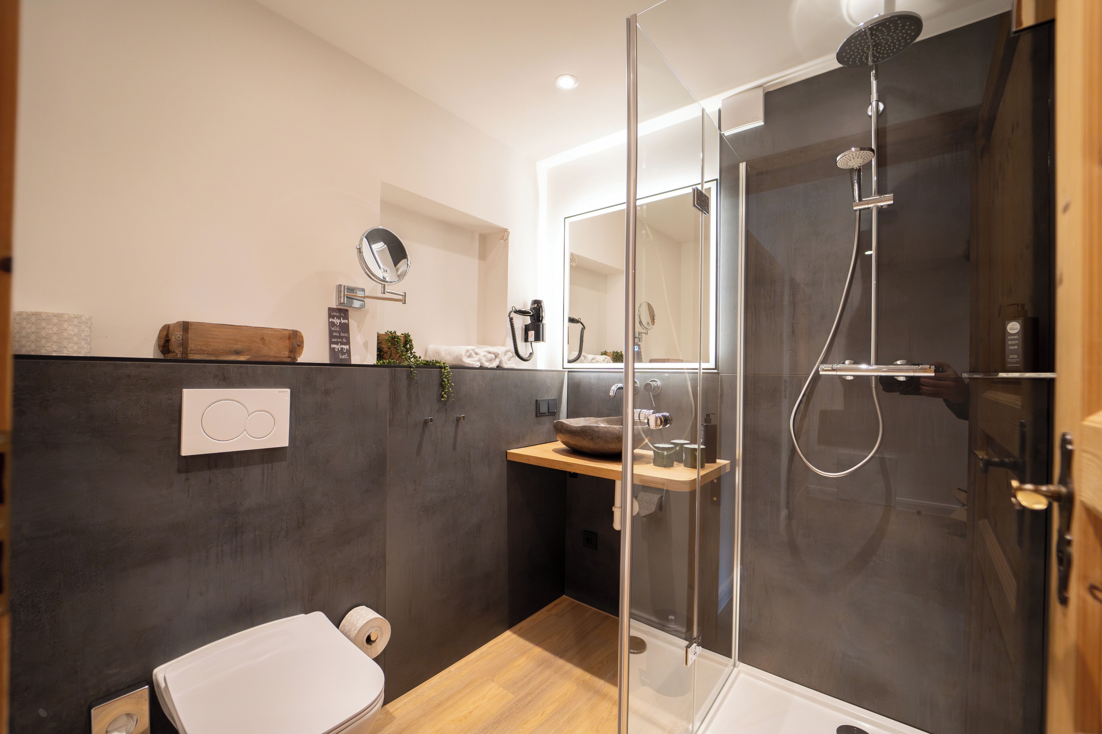 Une salle de bain moderne avec une douche à parois de verre, un meuble-lavabo en bois, des toilettes et un miroir.