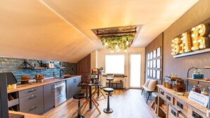 A modern kitchen with a bar area, wooden flooring, and a hanging light fixture.
