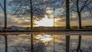 A park with trees and a lamppost reflecting in a puddle during sunset. - Apartment in Poppi With Shared Pool (Poppi)