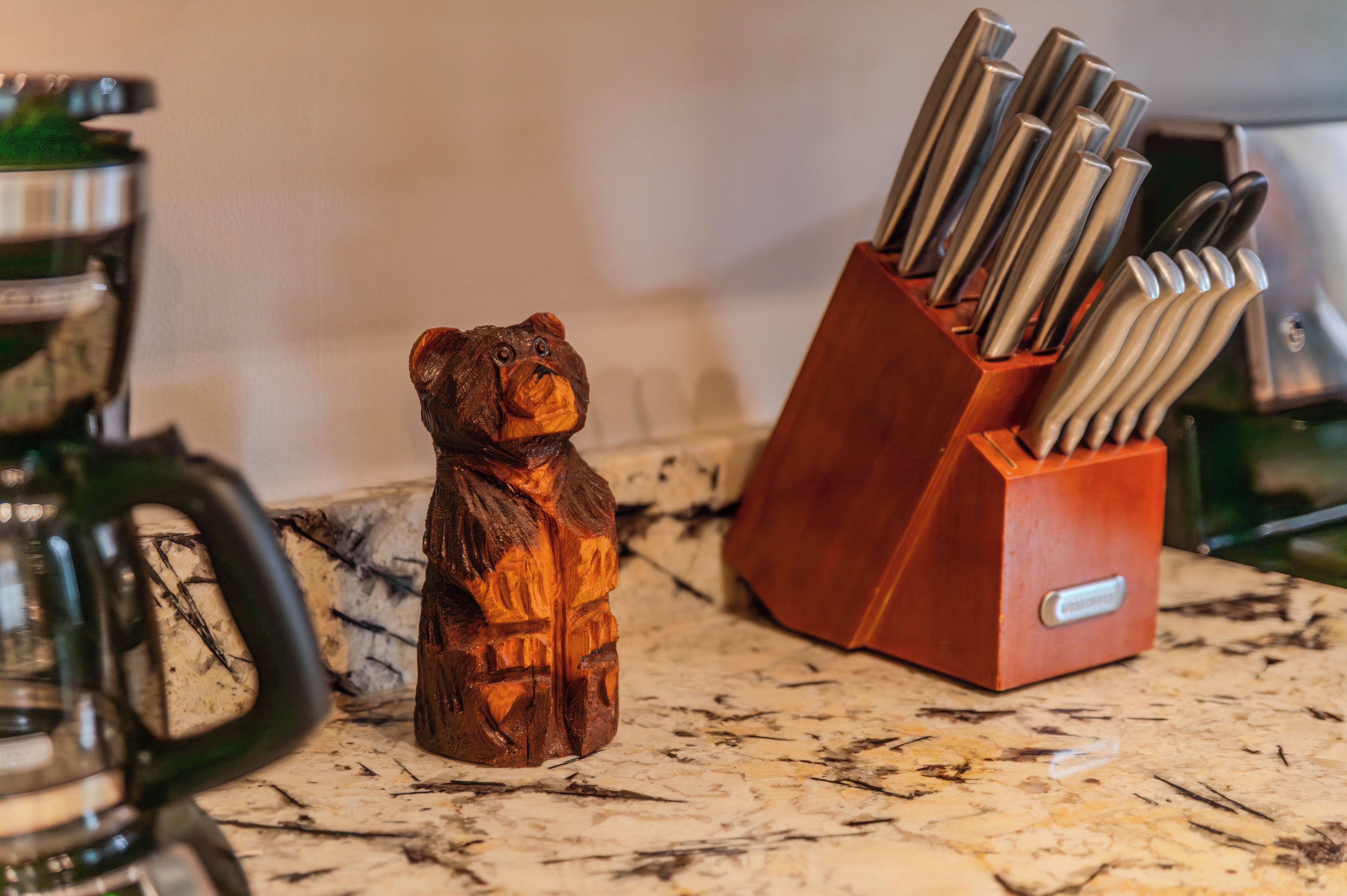 A kitchen counter with a wooden bear-shaped utensil holder and a knife block.