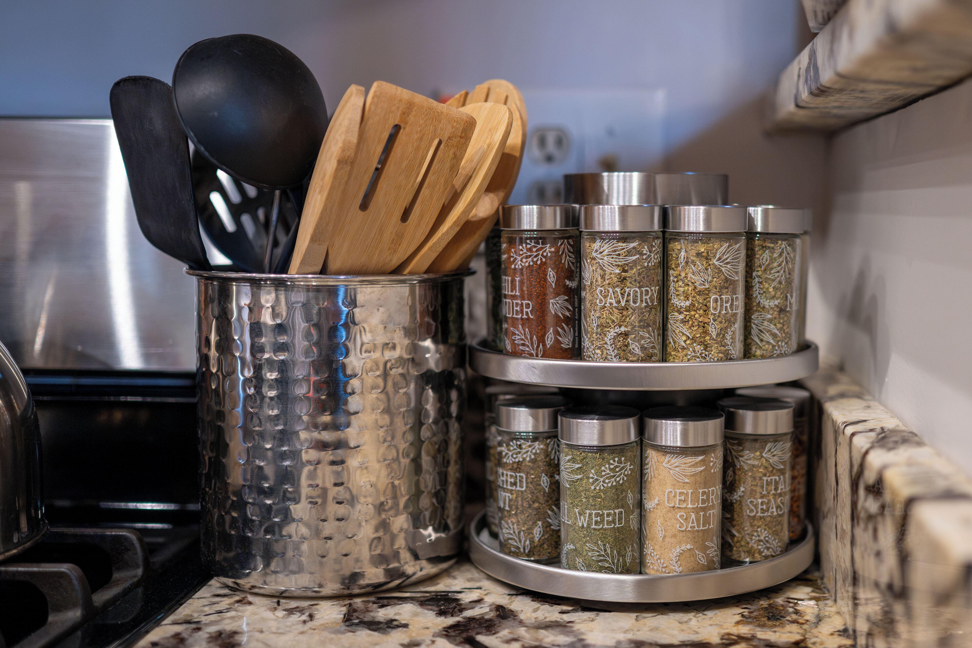 A kitchen counter with a spice rack holding various containers labeled with different spices and herbs.