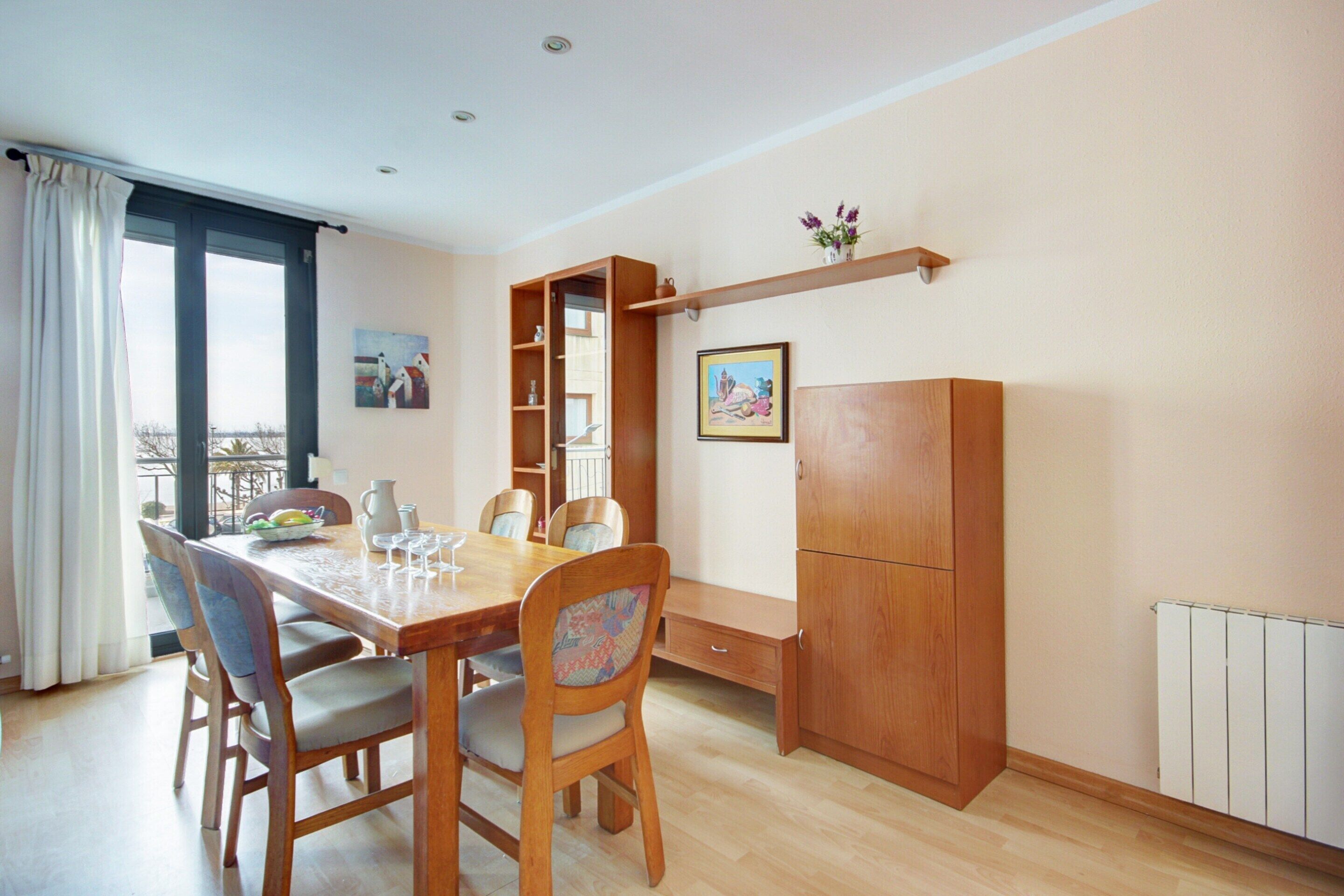 Een eetgedeelte met een houten tafel, stoelen en een inbouwkast.