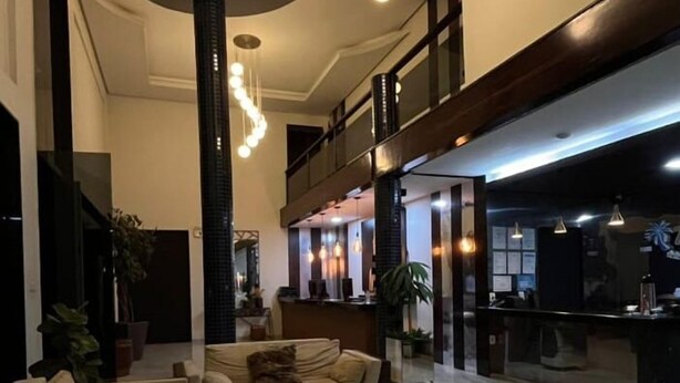 Un hall d’entrée spacieux avec un plafond haut, une colonne centrale et un comptoir d’accueil.