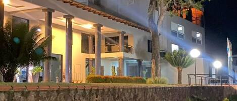 Un edificio moderno con fachada de piedra, ventanas grandes y un árbol en frente.