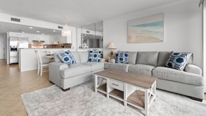 A modern living room with a grey sofa, a wooden coffee table, and a patterned rug. - Oceanfront- Pools- Hot Tub- Grill- Near Shops- Gym (North Myrtle Beach)