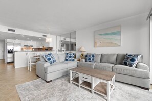 A modern living room with a grey sofa, a wooden coffee table, and a patterned rug.