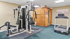 A gym with various exercise equipment, a treadmill, and a wooden cabinet. - Oceanfront- Pools- Hot Tub- Grill- Near Shops- Gym (North Myrtle Beach)