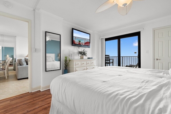 Une chambre avec un grand lit, un téléviseur fixé au mur, une commode et une vue sur l’extérieur grâce à une porte coulissante.