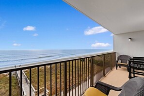 Un balcon avec vue sur l’océan, une terrasse en bois et du mobilier d’extérieur.