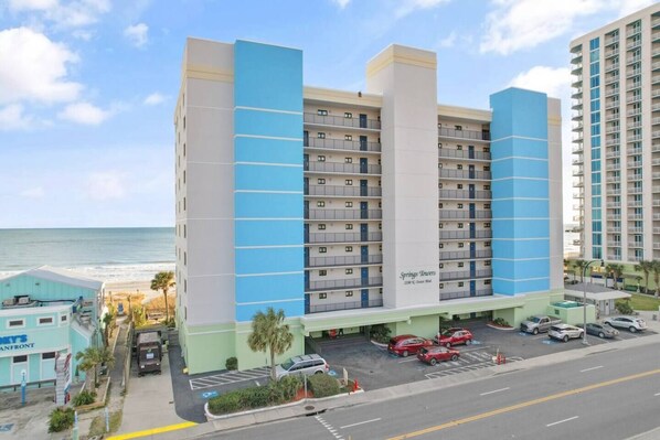 Un hôtel à plusieurs étages, doté d’une façade bleue et blanche remarquable, situé près d’une plage.