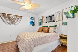 Une chambre à coucher avec un lit, un ventilateur de plafond et des œuvres d’art murales.
