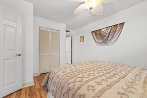 Un dormitorio con cama, ventilador de techo, armario e iluminación de pared.