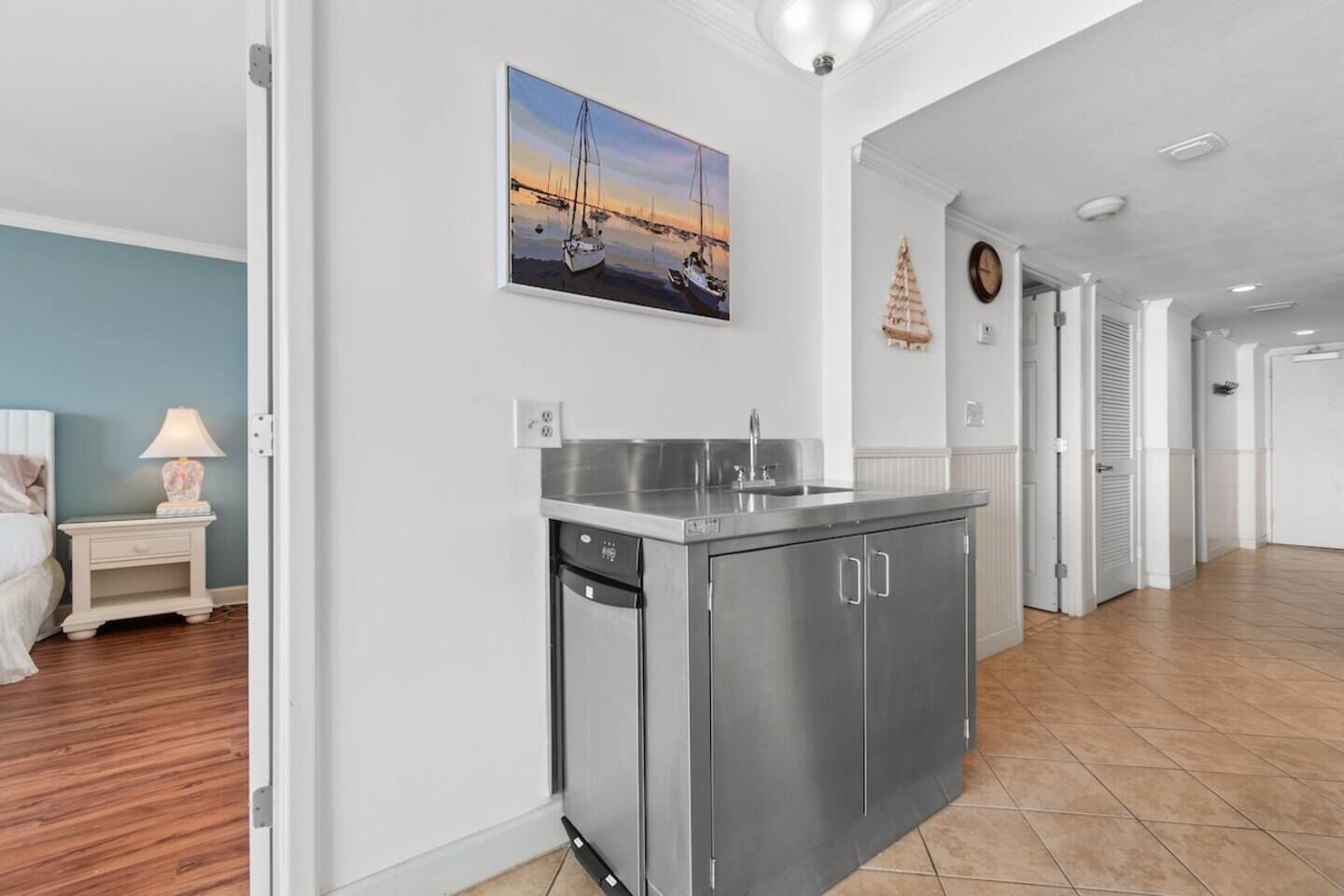 A modern kitchen with stainless steel appliances, a dining area with a table and chairs, and a hallway leading to other rooms.