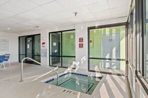 Una piscina interior con una profundidad de 90 centímetros, rodeada por paredes de vidrio y un letrero de precaución que indica agua poco profunda.