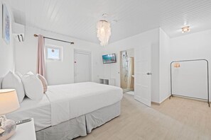 A bedroom with a bed, a bedside table, a lamp, a TV, a shower, and a door. - Backyard Bliss: 4BR Pool Home, 4Min to Eagle Beach (Noord)