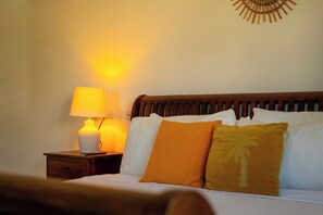 A hotel room with a bed, a nightstand, a lamp, and a wall decoration. - Backyard Bliss: 4BR Pool Home, 4Min to Eagle Beach (Noord)