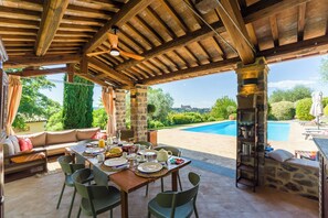 An outdoor dining area with a pool in the background. - Villa San Gabriele: Historic Charm and Modern Comfort (Orvieto)