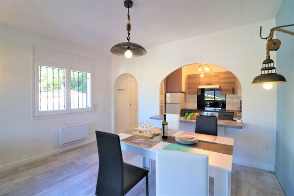 A modern kitchen with a built-in oven and a dining area with a white table and chairs.