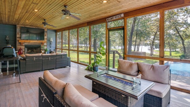 A spacious outdoor living area with a wooden ceiling, a large TV, and a grill. - Refined Lake Retreat on Lake Fork in Emory, TX, fishing, kayaking, antiquing (Emory)