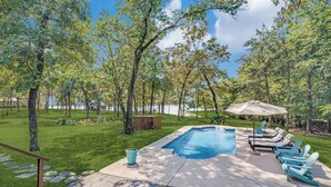 A backyard with a swimming pool, stone patio, and outdoor furniture. - Refined Lake Retreat on Lake Fork in Emory, TX, fishing, kayaking, antiquing (Emory)