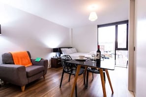 Une chambre moderne comprenant un lit, un canapé, une table à manger et offrant une vue sur l’extérieur grâce à une grande fenêtre.
