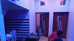 A room with a herringbone wooden floor, a fan, a red chair, and two doors labeled 101 and 102. - Dev In & homestay (Faizabad)