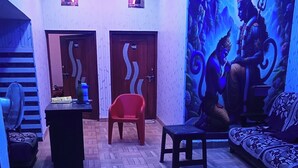 A room with a herringbone floor, two doors labeled 101 and 102, a red chair, a black stool, and a wall mural depicting a mythological scene. - Dev In & homestay (Faizabad)