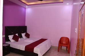 A bedroom with a bed, a nightstand, a red chair, and purple walls. - Dev In & homestay (Faizabad)