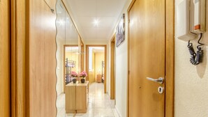 Un pasillo con puertas de madera, un teléfono y una pequeña mesa con flores.