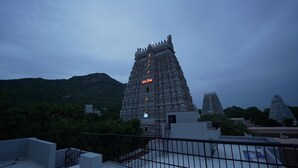 A temple complex with tiered architecture, surrounded by greenery and hills. - ARUDRA RESIDENCY (Tiruvannamalai)