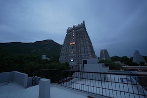 A temple complex with tiered architecture, surrounded by greenery and hills. - ARUDRA RESIDENCY (Tiruvannamalai)
