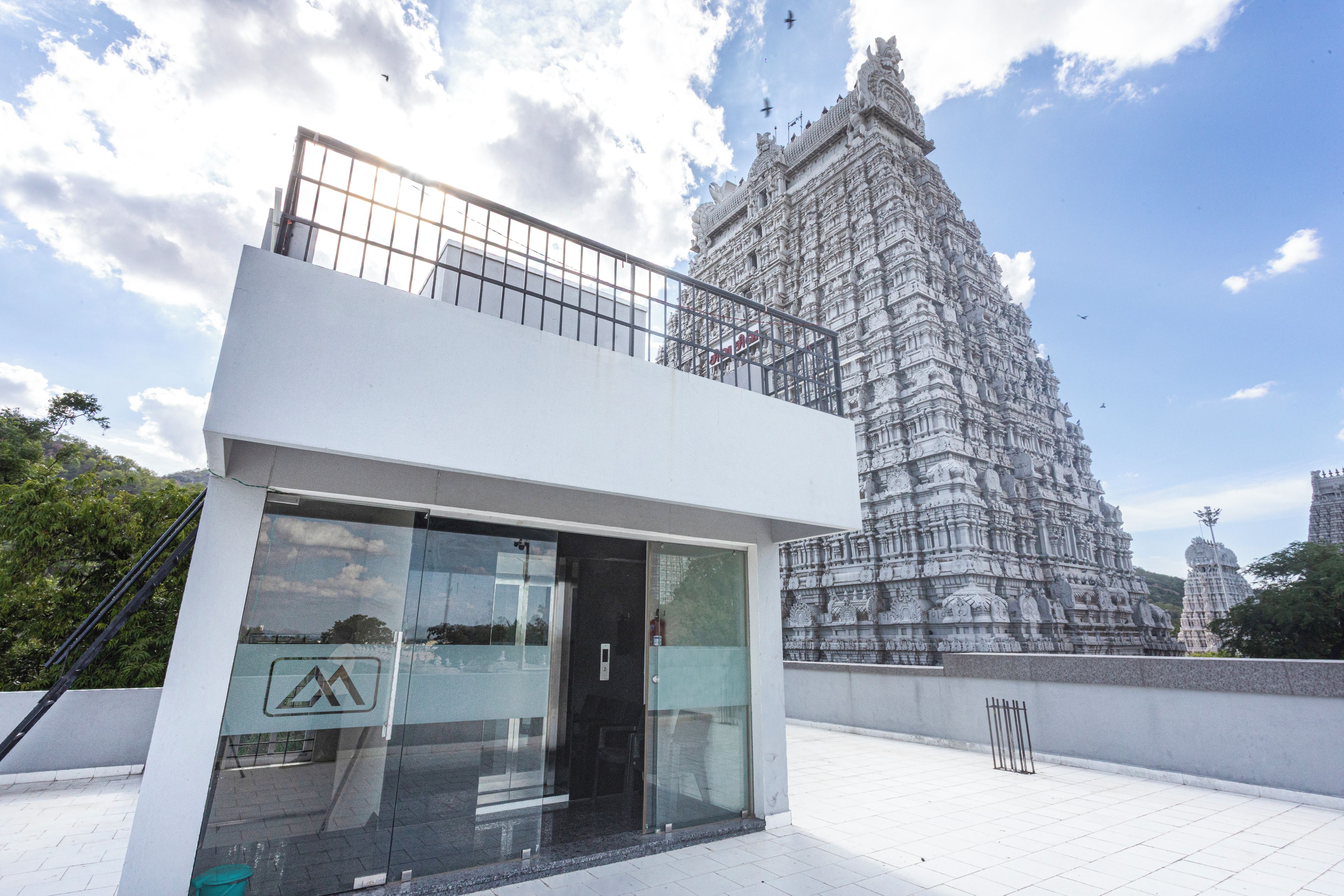 Un edificio moderno con fachada de vidrio y un templo tradicional al fondo.