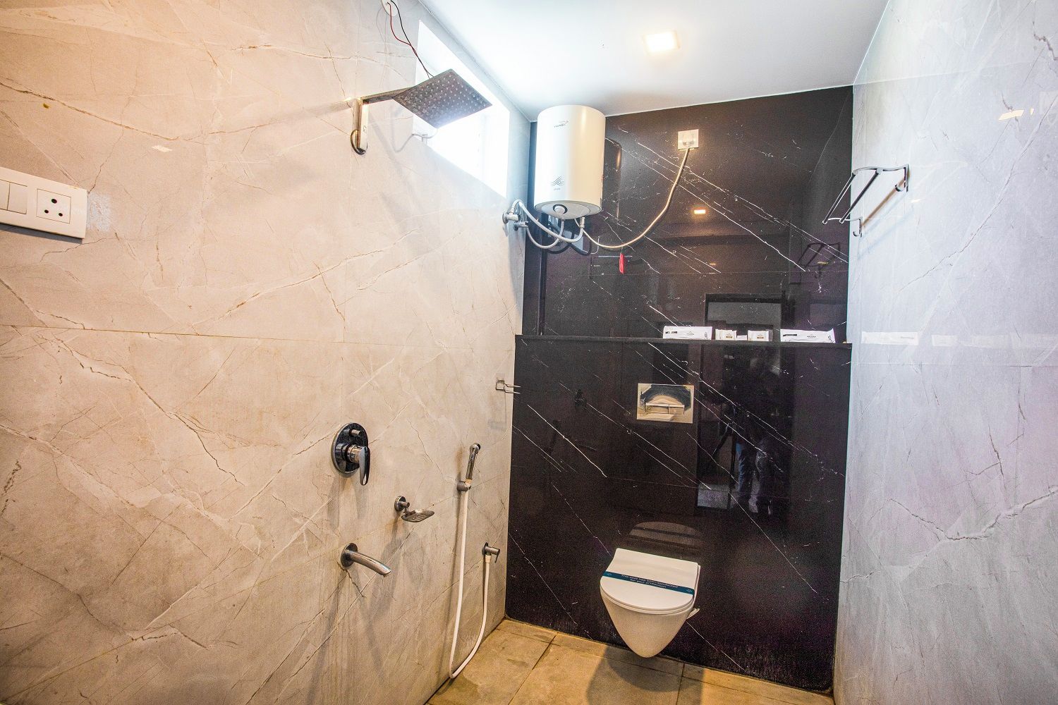 A modern bathroom with a shower, toilet, and a marble wall.