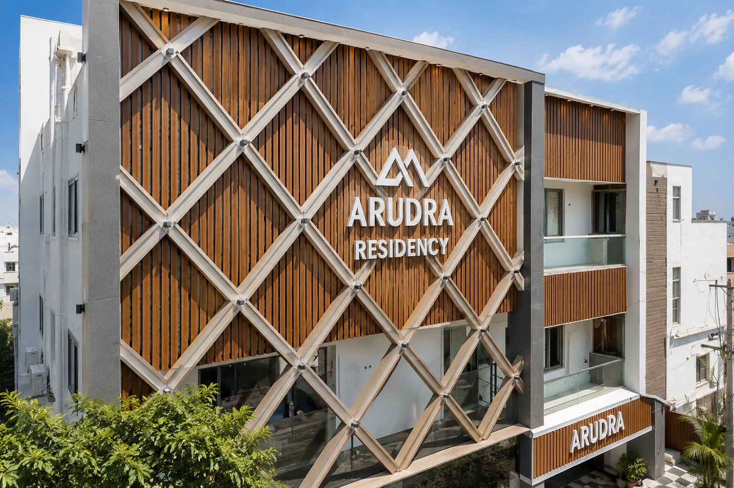 Ein modernes Gebäude mit Holzfassade, auf der das Schild 'ARUDRA RESIDENCY' gut sichtbar angebracht ist.