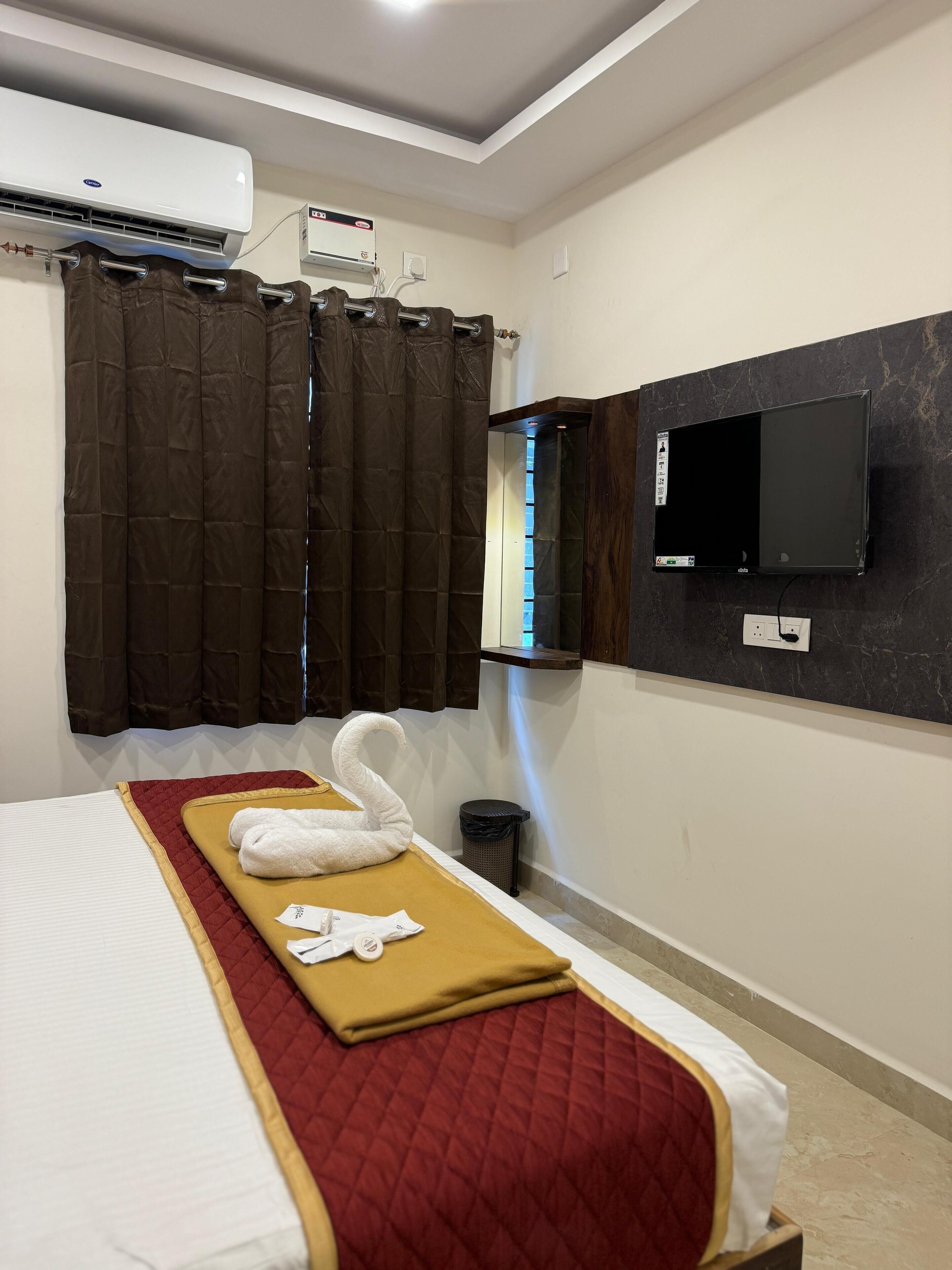 Een hotelkamer met een bed, een aan de muur bevestigde televisie en een airconditioning.