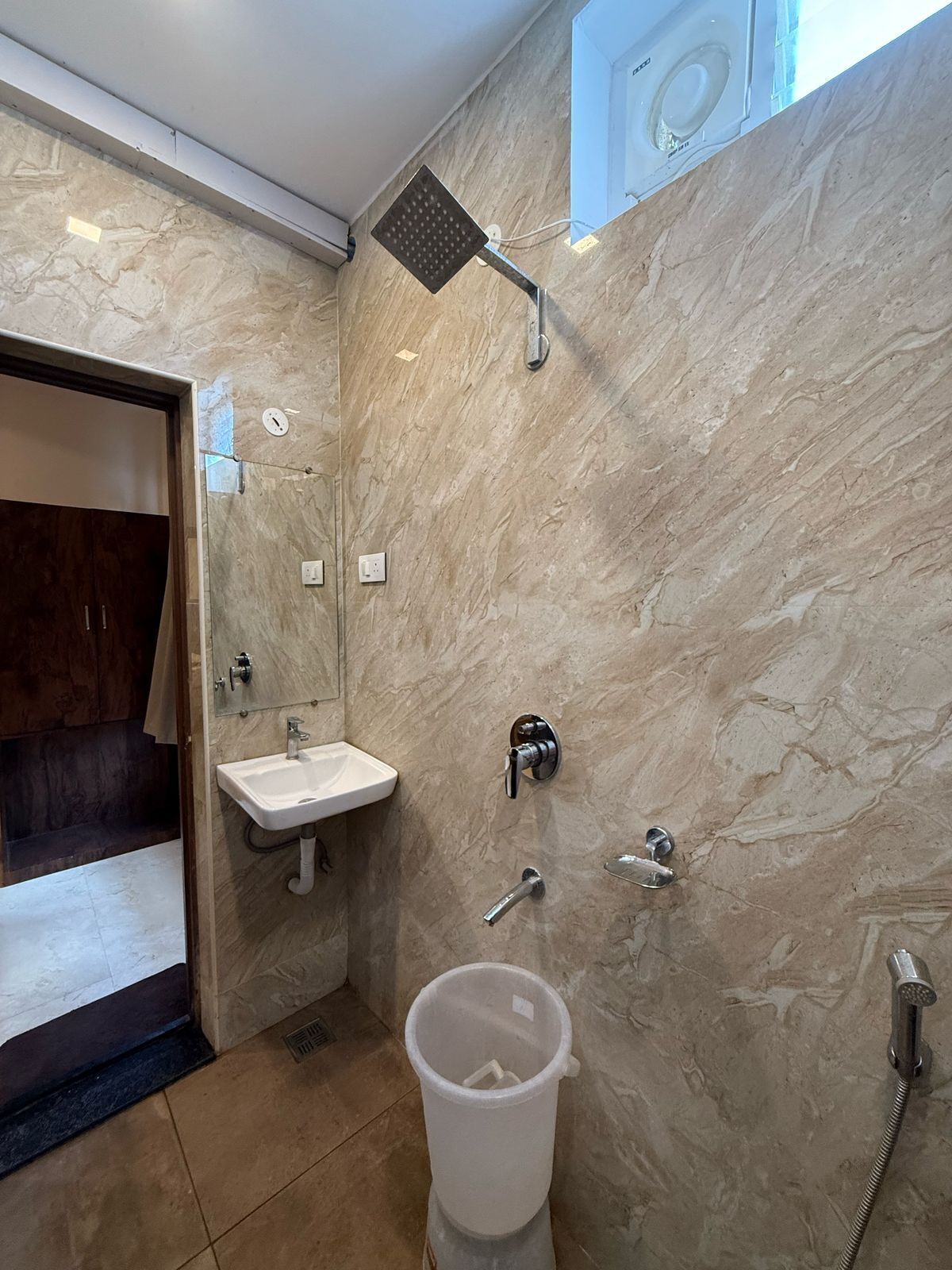 Ein modernes Badezimmer mit Marmorwand, Dusche, Waschbecken und Toilette.