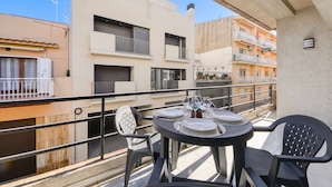 Ein Balkon mit Esstisch und Stühlen, mit Blick auf ein Wohngebiet mit Gebäuden.