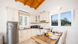 Eine moderne Küche mit Edelstahl-Kühlschrank, Esstisch aus Holz und weißen Schränken.