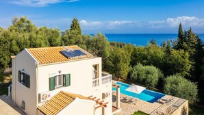 Eine Villa mit Pool, Meerblick und Garten.
