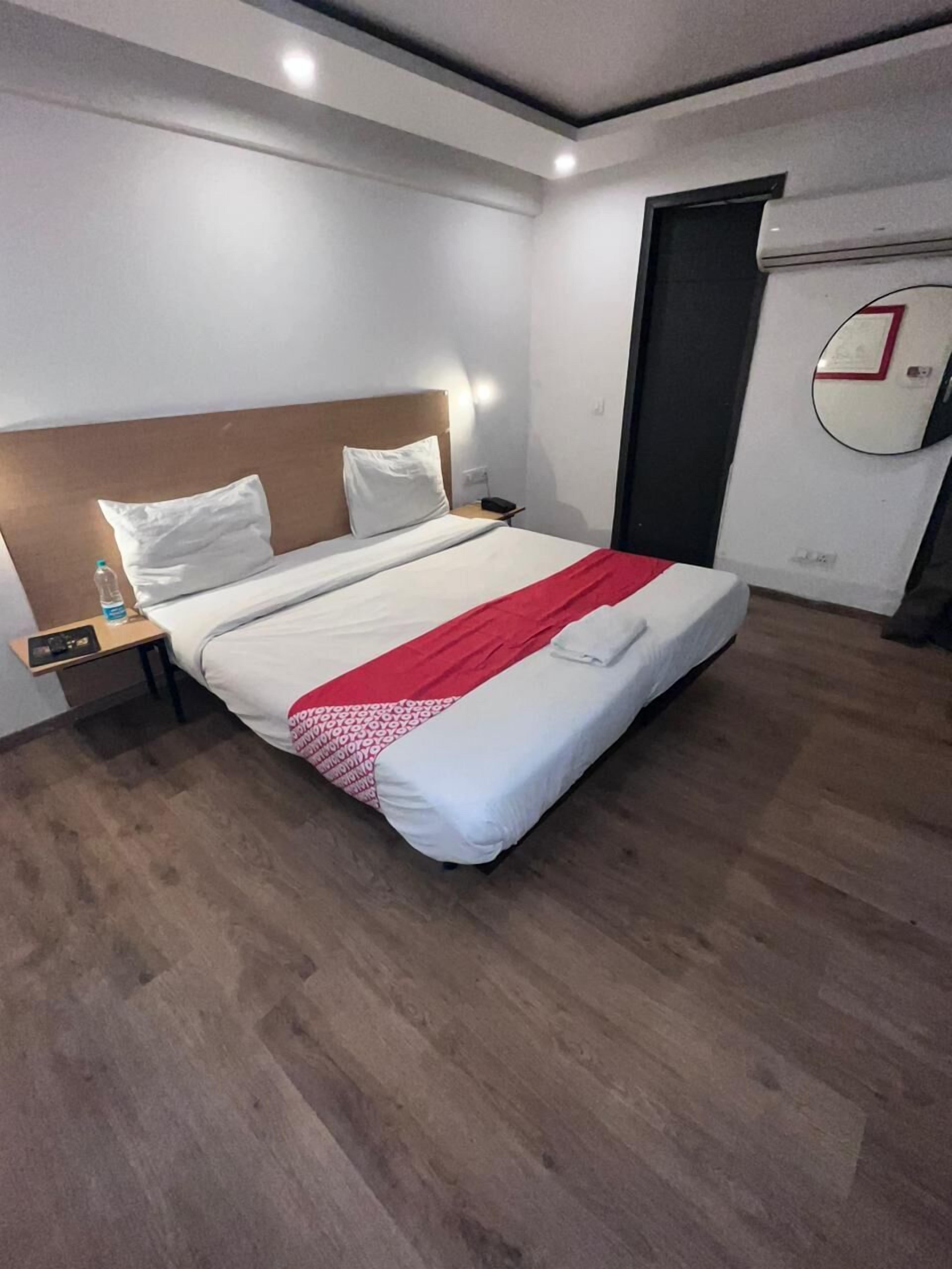 Une chambre d’hôtel équipée d’un lit, d’une table de chevet, d’une bouteille d’eau et d’un climatiseur fixé au mur.