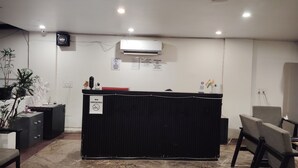 A reception area with a black counter, marble floor, and a sign indicating no smoking. - Hotel Arena  (Gurugram)