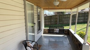 A covered porch with a bench, a table with a potted plant, and a stone wall. - Boho Bungalow  2-bedroom house Professionally Cleaned in delightful Fort Smith (Fort Smith)