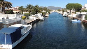 A canal with boats docked on both sides, surrounded by buildings and palm trees. - Apartment Empuriabrava Near Sandy Beach (Castello d'Empuries)