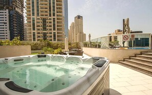 A rooftop pool area with hot tubs, surrounded by high-rise buildings.