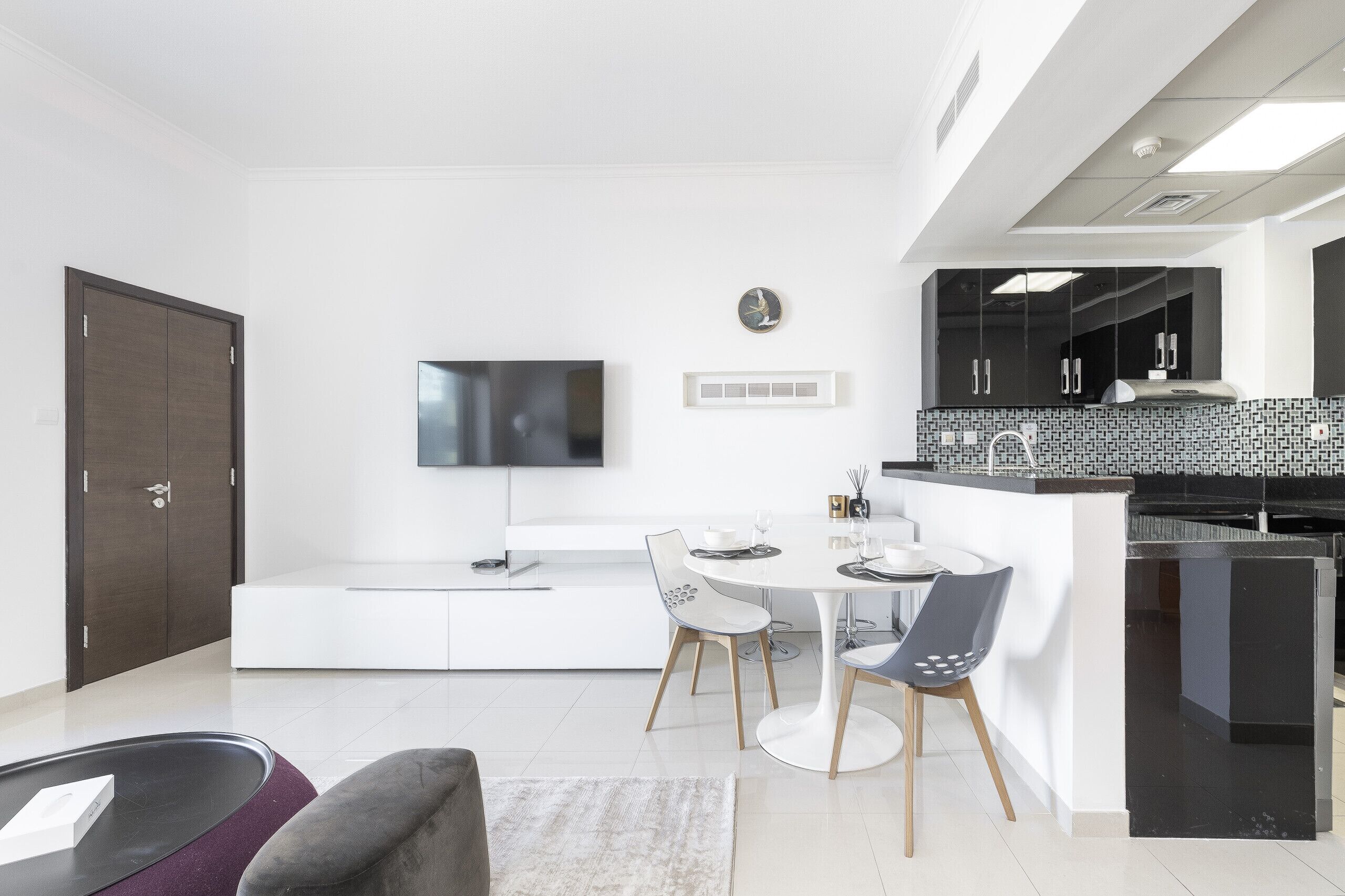 Una cocina moderna con encimera negra, armarios blancos y salpicadero de azulejos.