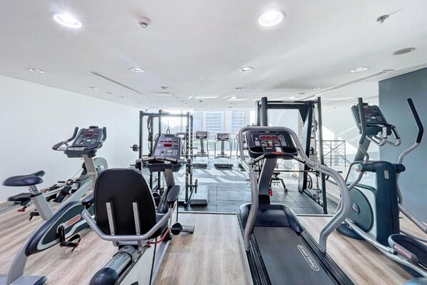 Un gimnasio con cintas de correr, elípticas y equipo de pesas.