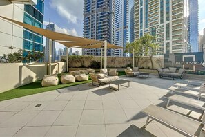 Un espace extérieur aménagé en terrasse, avec des chaises longues, un auvent et un panneau indiquant « JARDIN BOTANIQUE ».