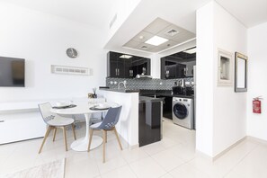 A modern kitchen with a central island, a dining area with two chairs, and a washing machine.